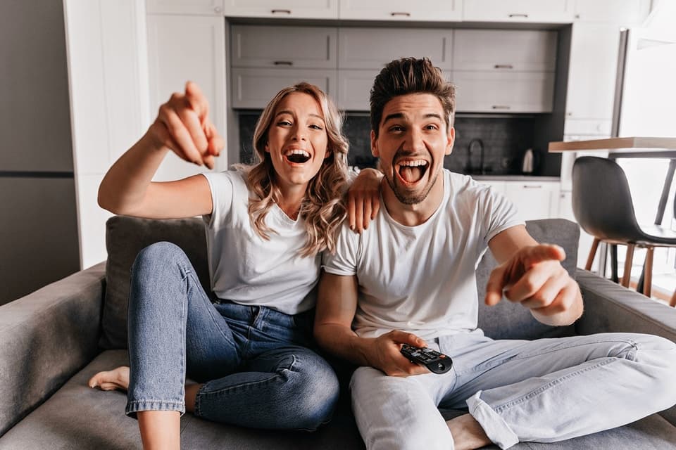 Happy couple watching IPTV with remote control